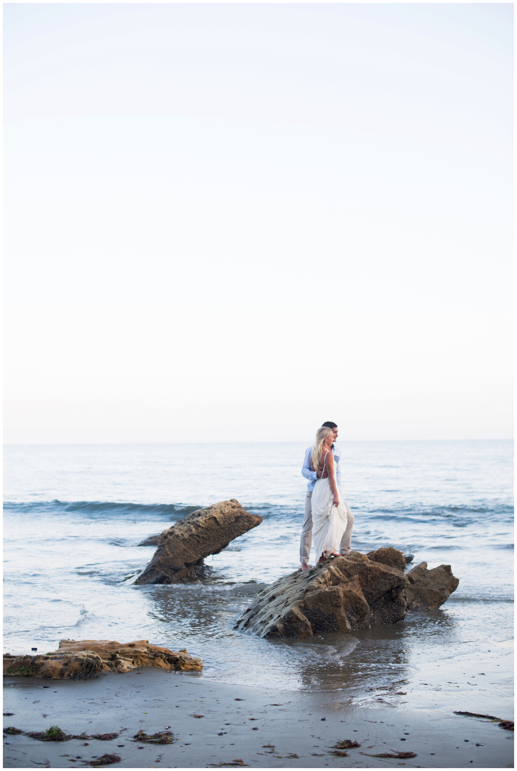 A sunset Northern California beach rehearsal dinner photo session on the cliffs and by the ocean with mossy rocks and bare feet the night before they got married with beach engagement session inspiration