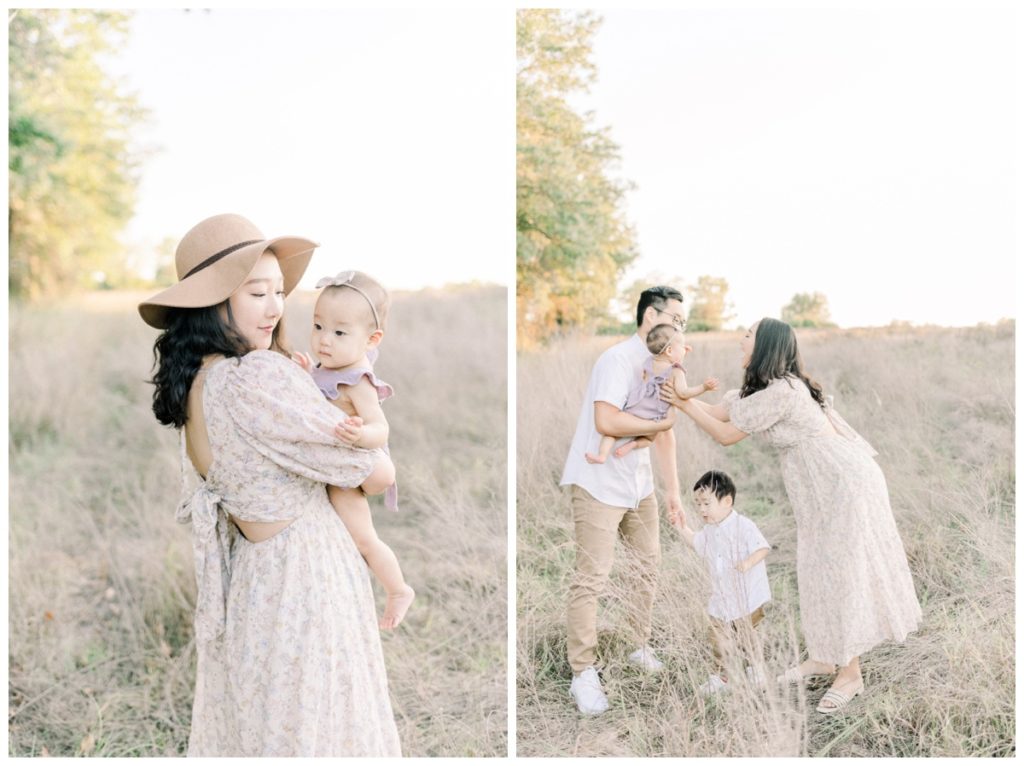 Photo of a young mom standing in a natural light wheat field wearing a wide brimmed hat looking down at her daughter in her arms. 