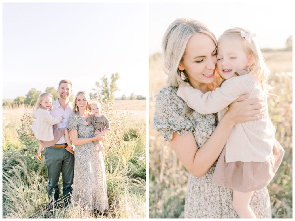 A picture of a family of four standing in a field at sunset while the dad holds his toddler daughter and the wife is holding their son while they all smile at the camera. 