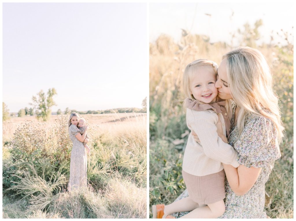 A photo of a young mom hugging her toddler son in a field at sunset while she wears a ditsy floral dress. 