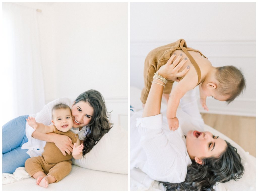 Photo of a mom in a well lit natural light room with white walls laying on her side holding her nine month old son smiling and looking at the camera. 