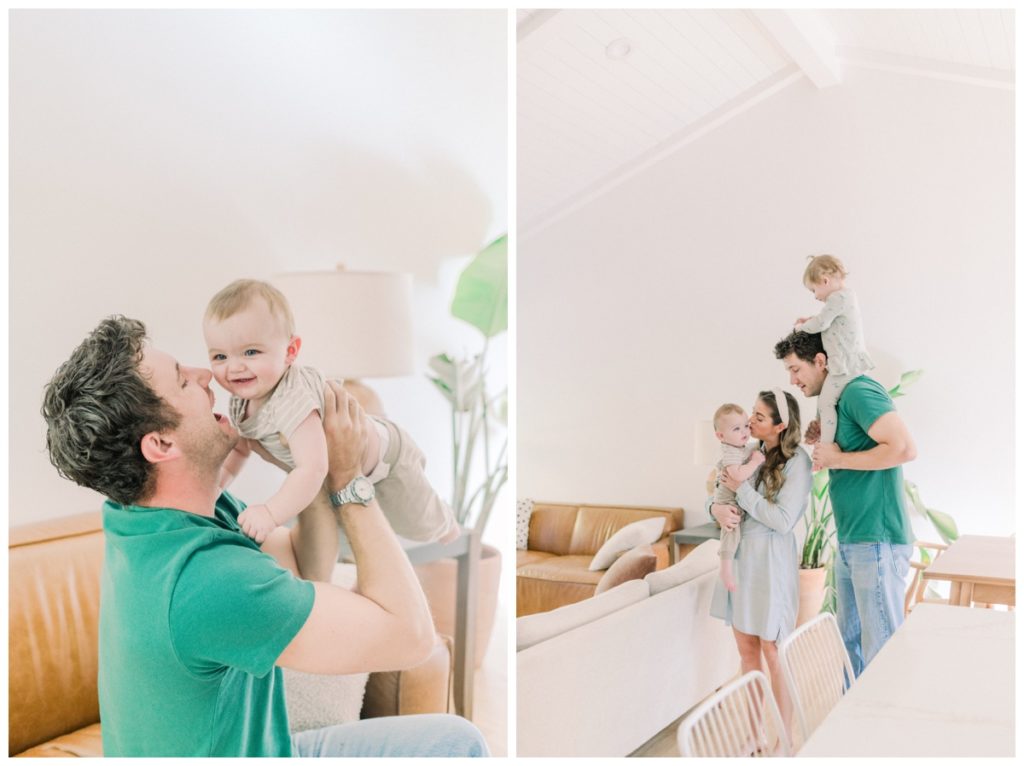 Photo of a young family standing in a modern home while the young mom wears a light jean dress and holds her toddler son and their daughter is one the dad's shoulders. 