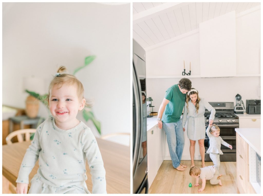 Photo of a young family dancing together in a white kitchen while the dad leans against the counter and the mom twirls her daughter wearing a jean bow. 