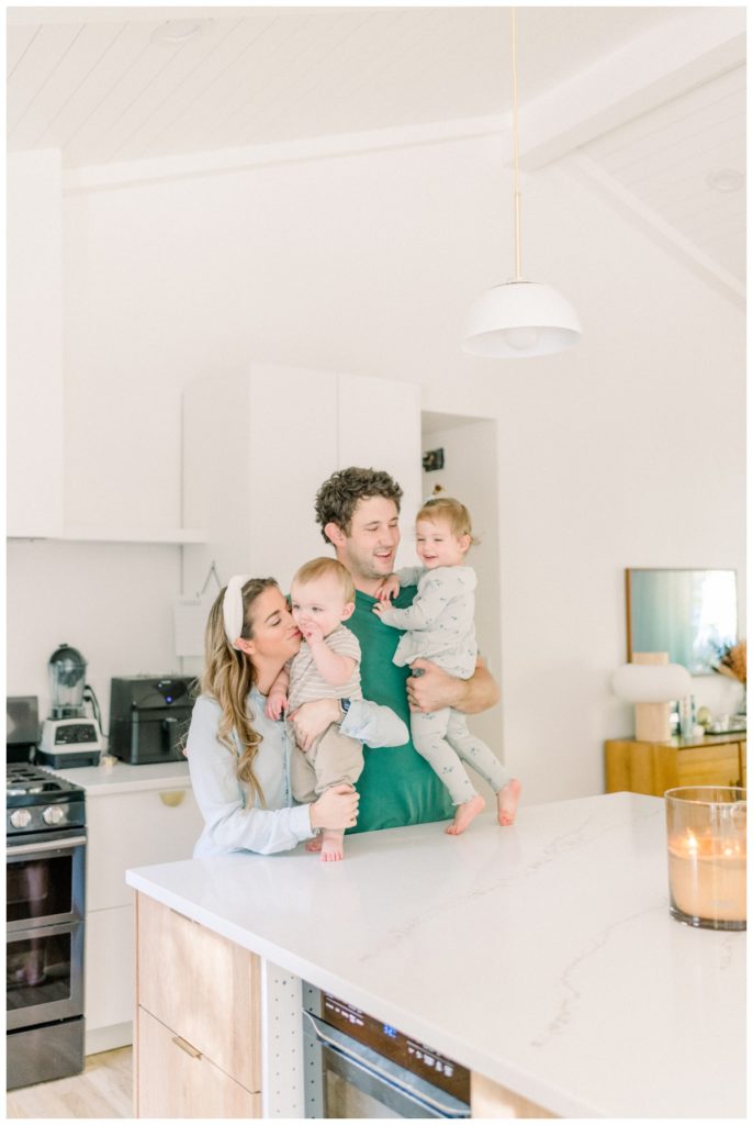 Picture of a young family hugging one another in a clean, modern white kitchen.